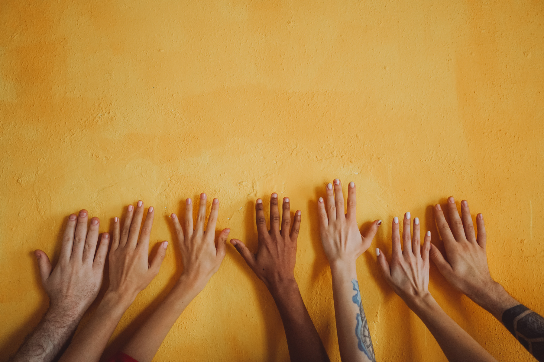 Diverse Hands on Yellow Wall